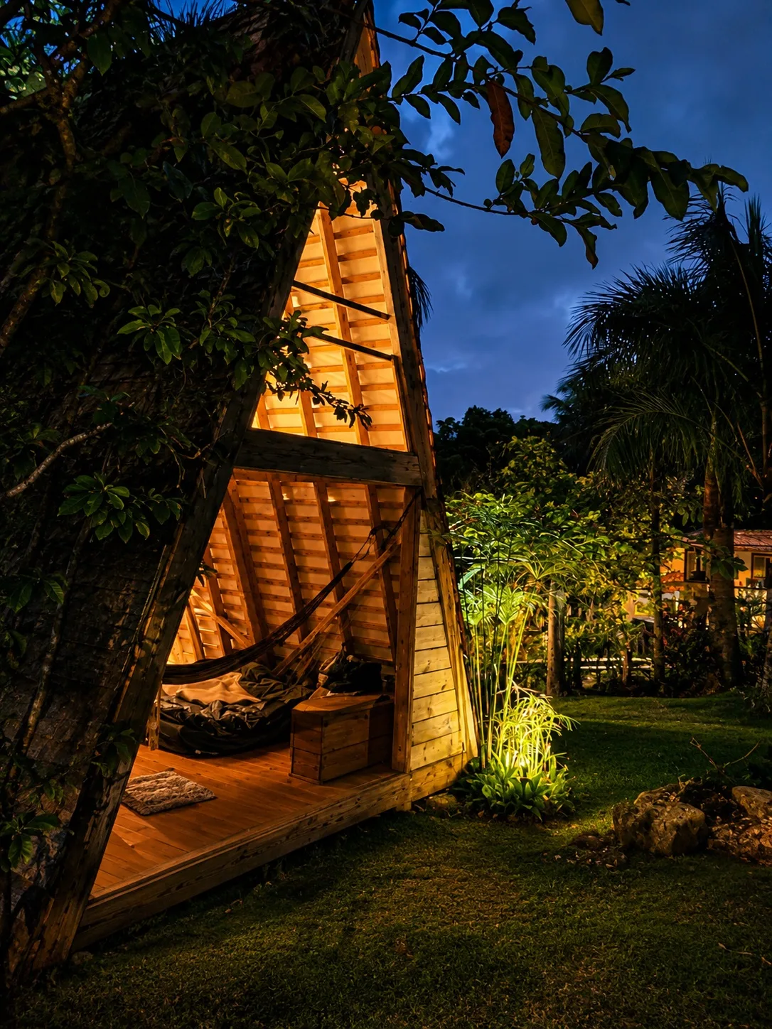 A-frame des Vendredis éclairée la nuit dans le jardin tropical