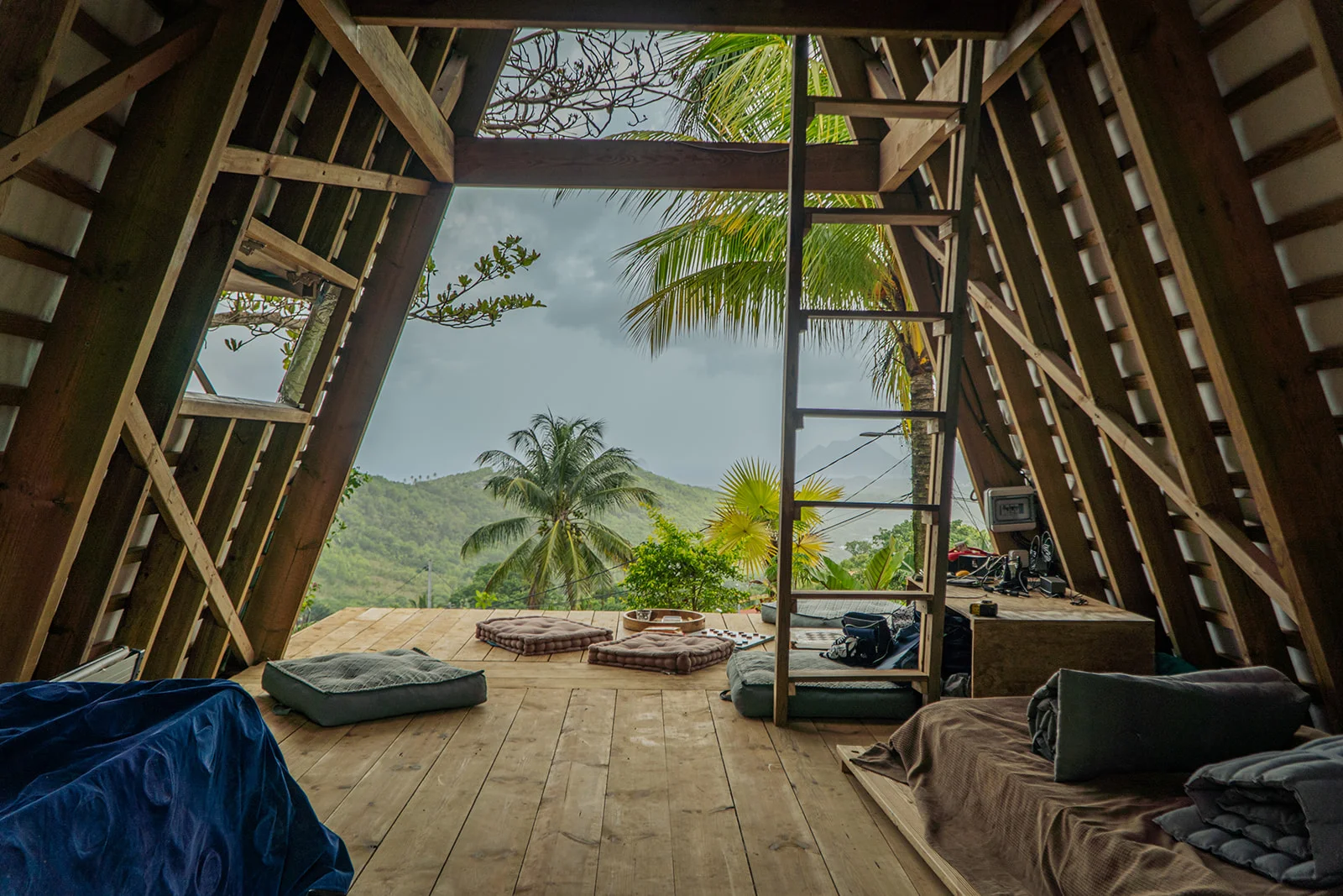 Wood floor, cushions, ladder to the mezzanine, and the hills framed in the opening