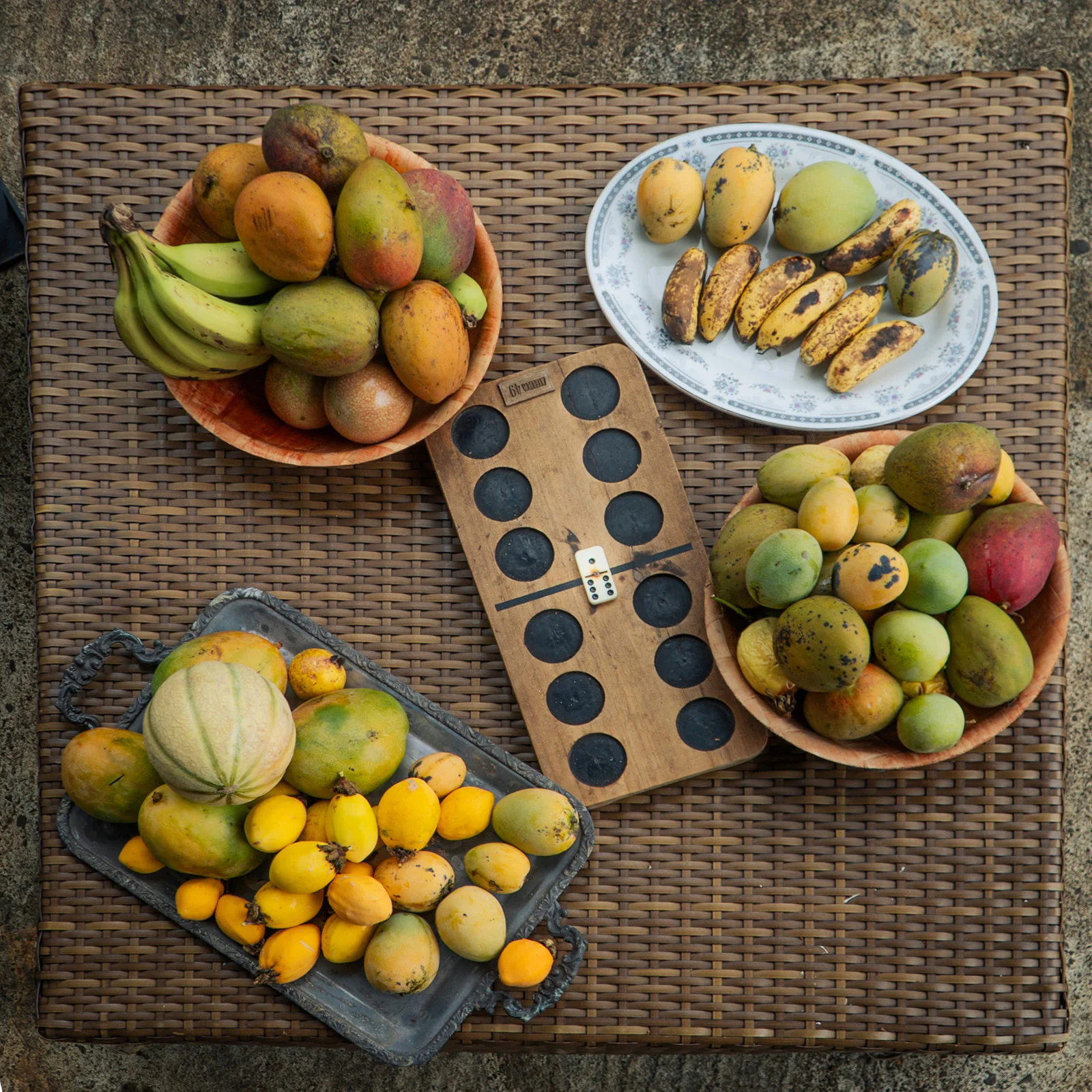 Top view of tropical fruit baskets and an awalé board at the centre